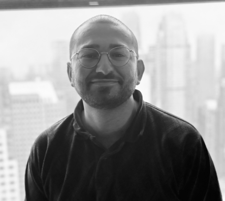 Black and white photo of Josh Binderman smiling in front of a window