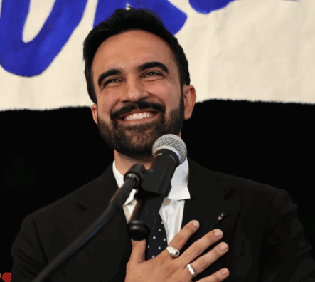 Zohran Mamdani smiles at a microphone on his primary election night.